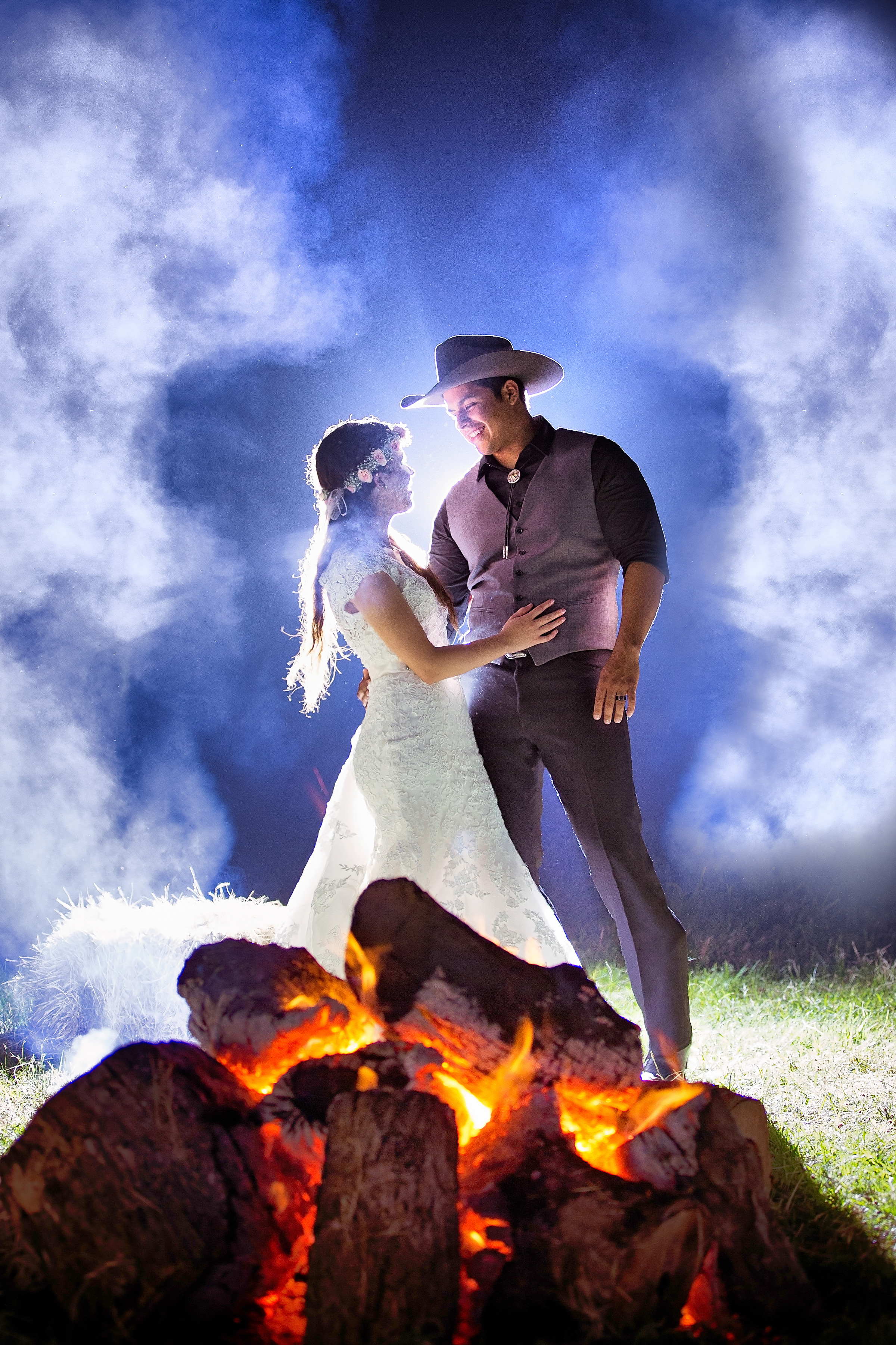 Bride and groom dancing beside a fire under dramatic blue light