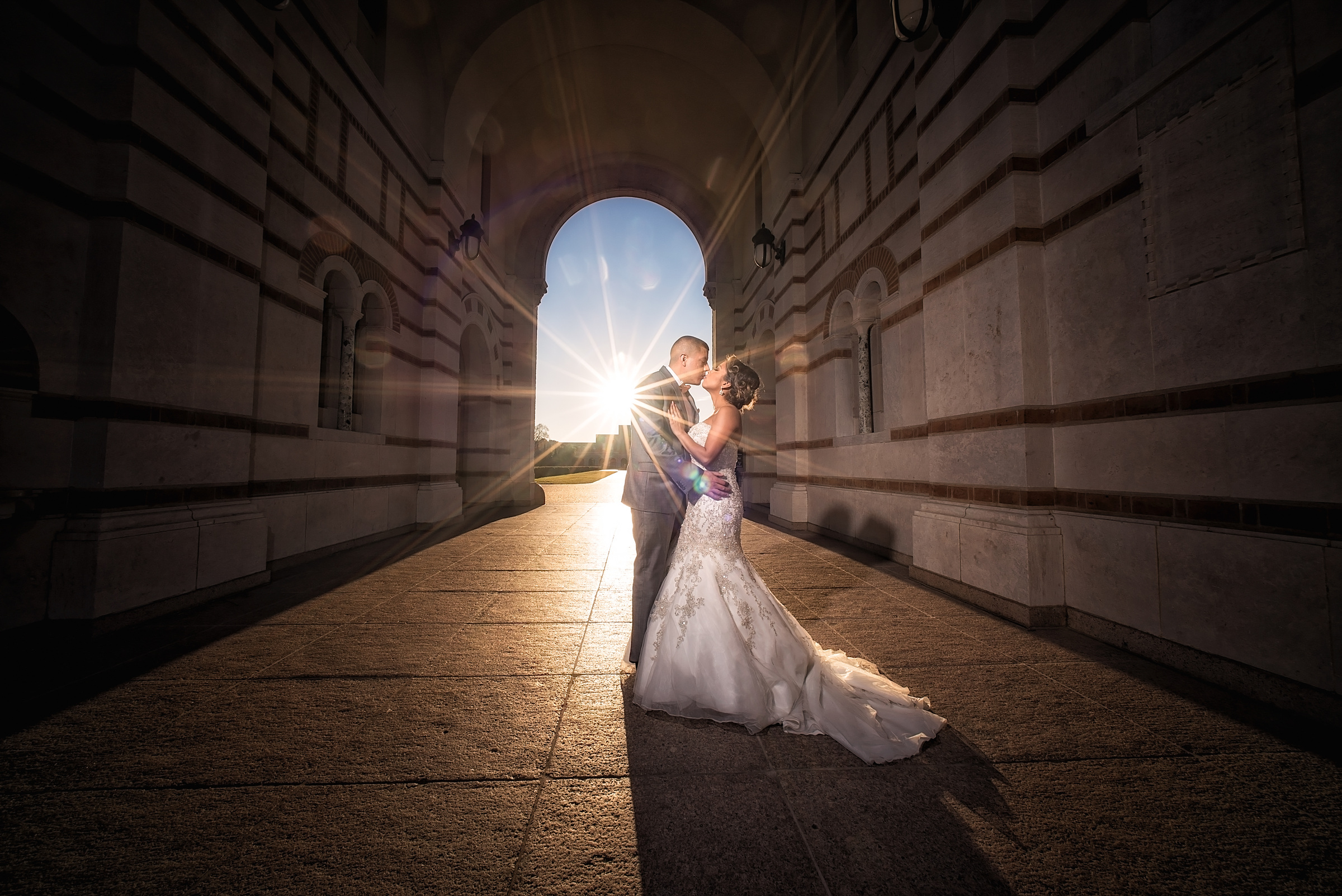 Bride and groom kissing beneath a sunburst at a Houston wedding venue